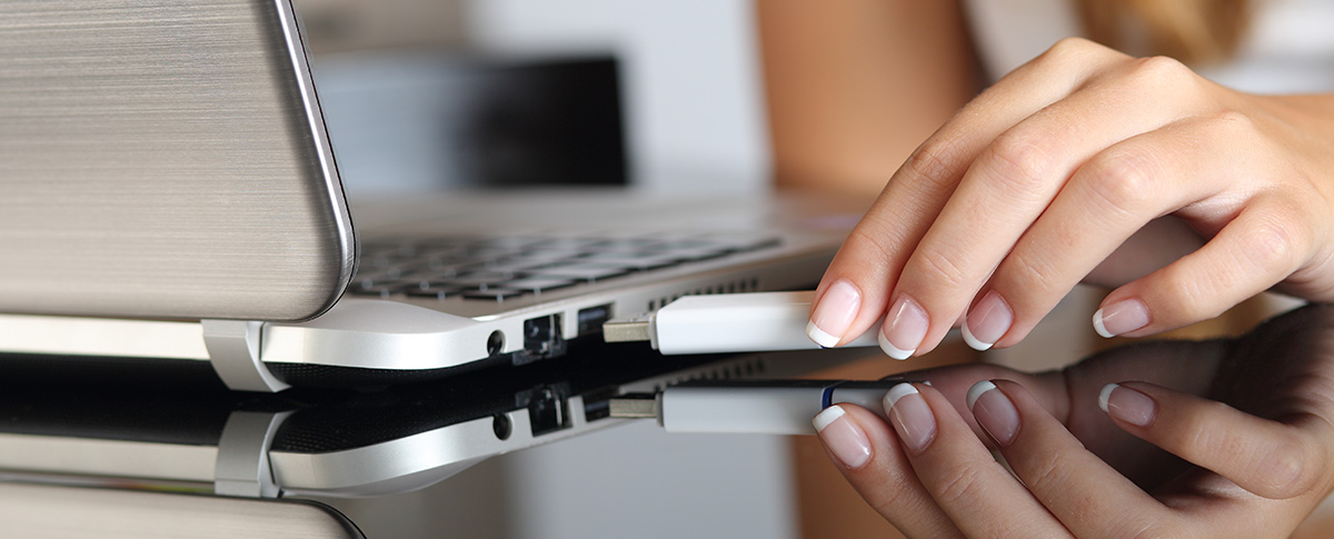 Woman Plugging an USB Drive into Laptop